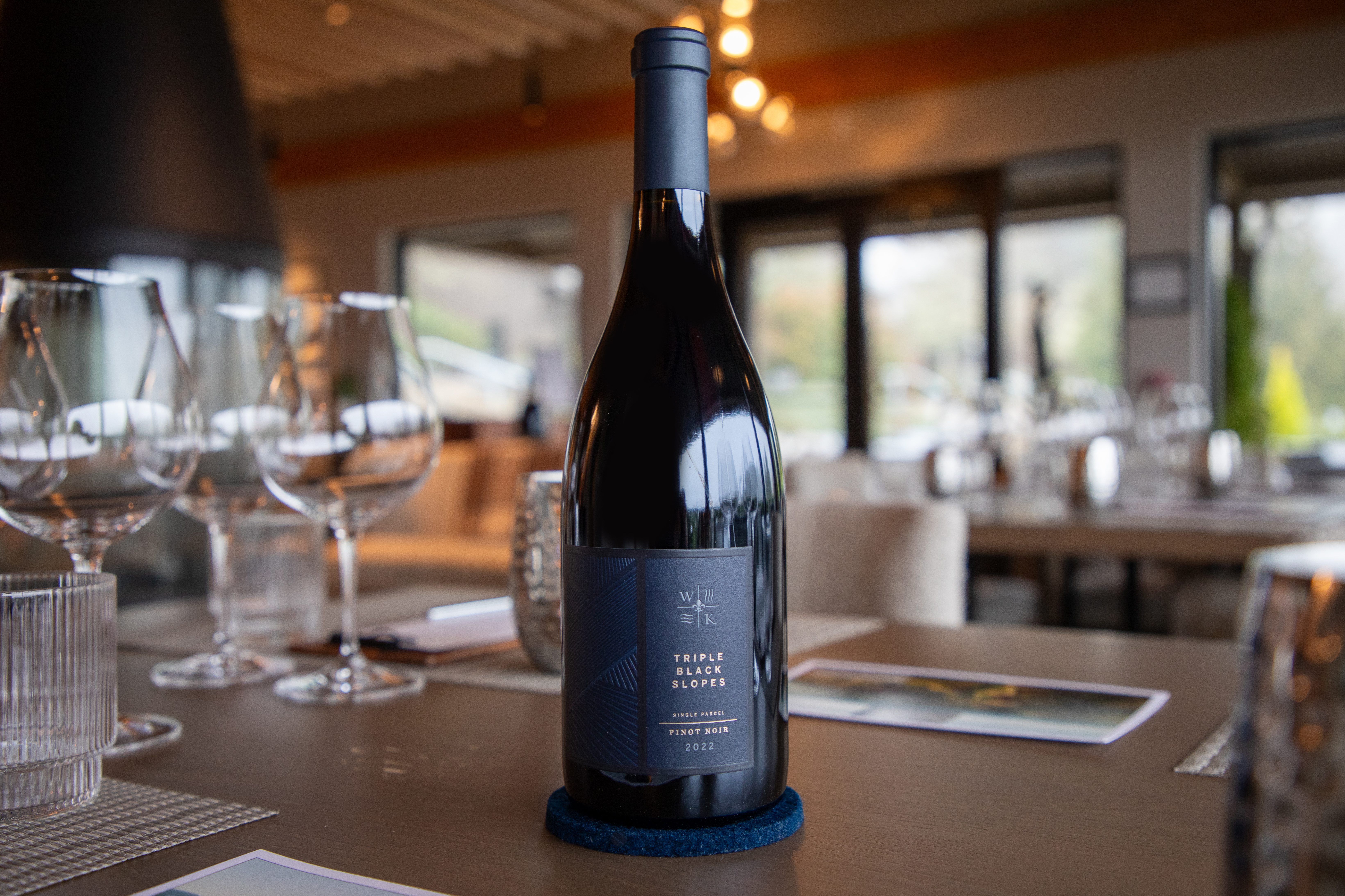 A bottle of pinot noir being poured into a glass